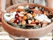 A vibrant rustic salad featuring fresh fruits, greens, and cheese in a wooden bowl, perfect for summer meals.